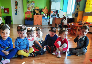 Dzieci siedzą w misiowych opaskach z uszami
